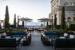 Rooftop event space with seating, umbrellas, and greenery overlooking a cityscape at dusk in Manhattan.