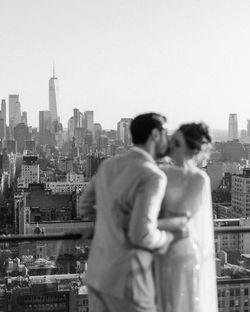 Couple embracing on a Manhattan rooftop event space with a clear view of the New York City skyline.